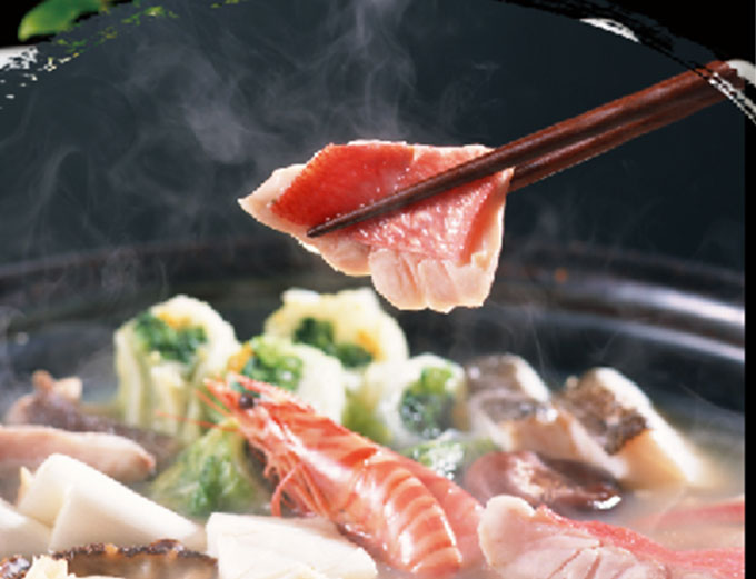 A steaming hot pot with shrimp, fish and vegetables